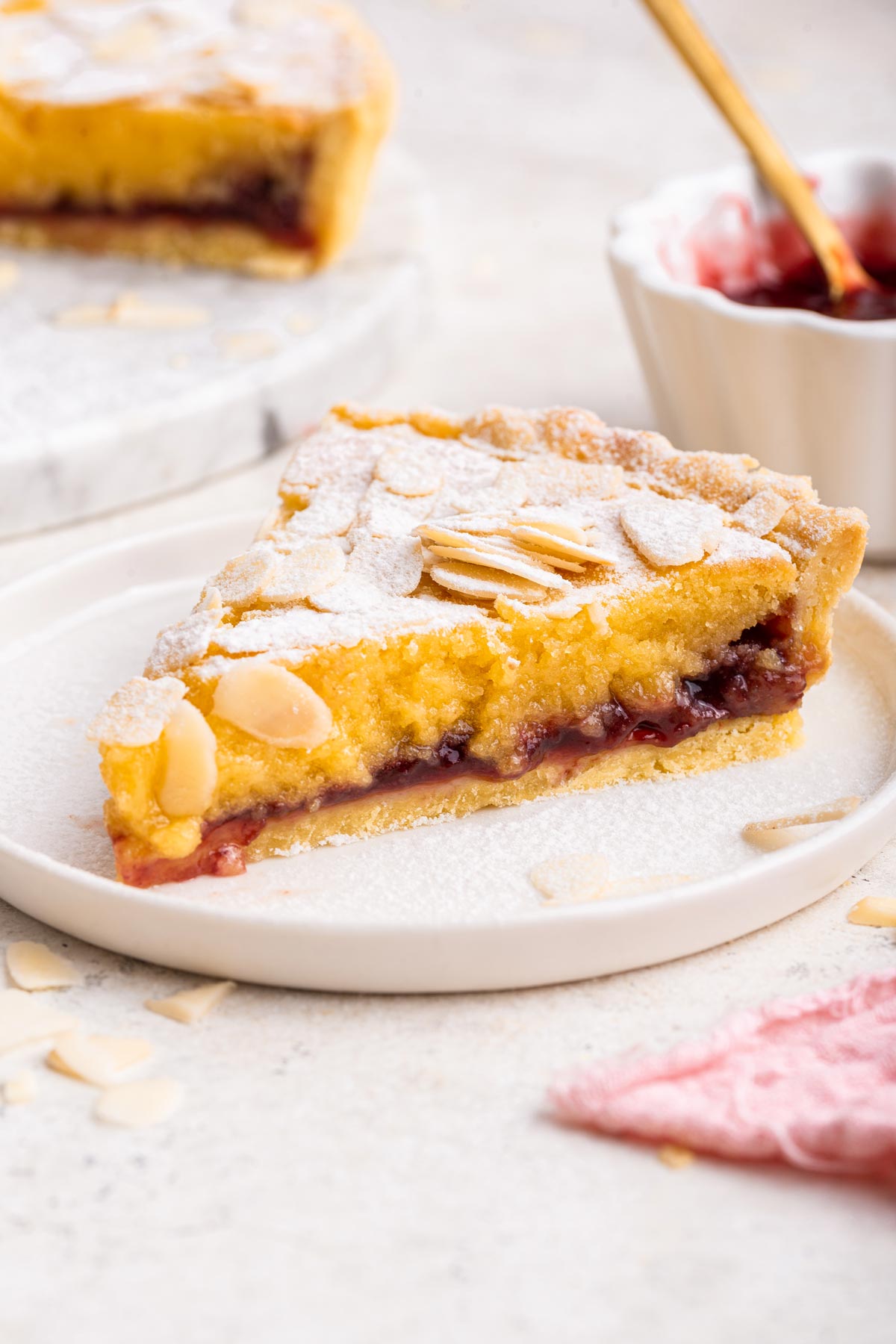 side view of a single slice of bakewell tart showing a thick layer cherry jam.