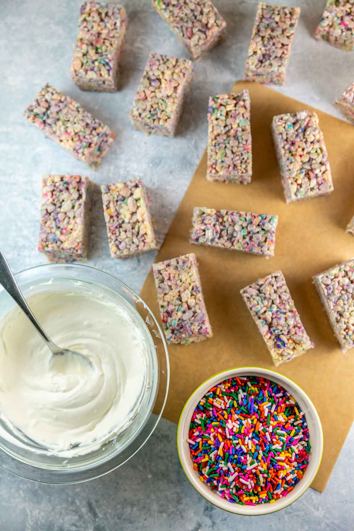 rice krispie treats cut into rectangles next to melted chocolate and sprinkles.