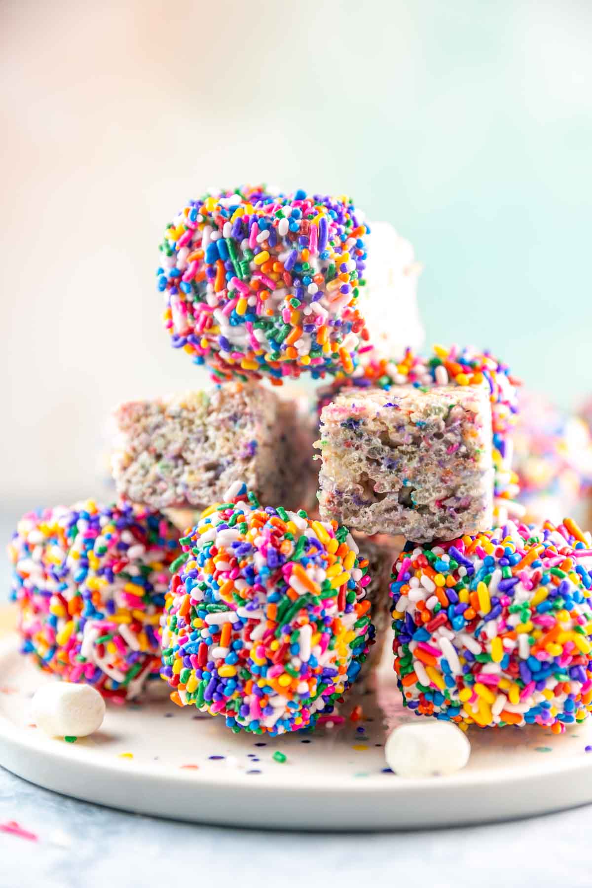 sprinkle rice krispie treats dipped in chocolate stacked on a dessert plate.