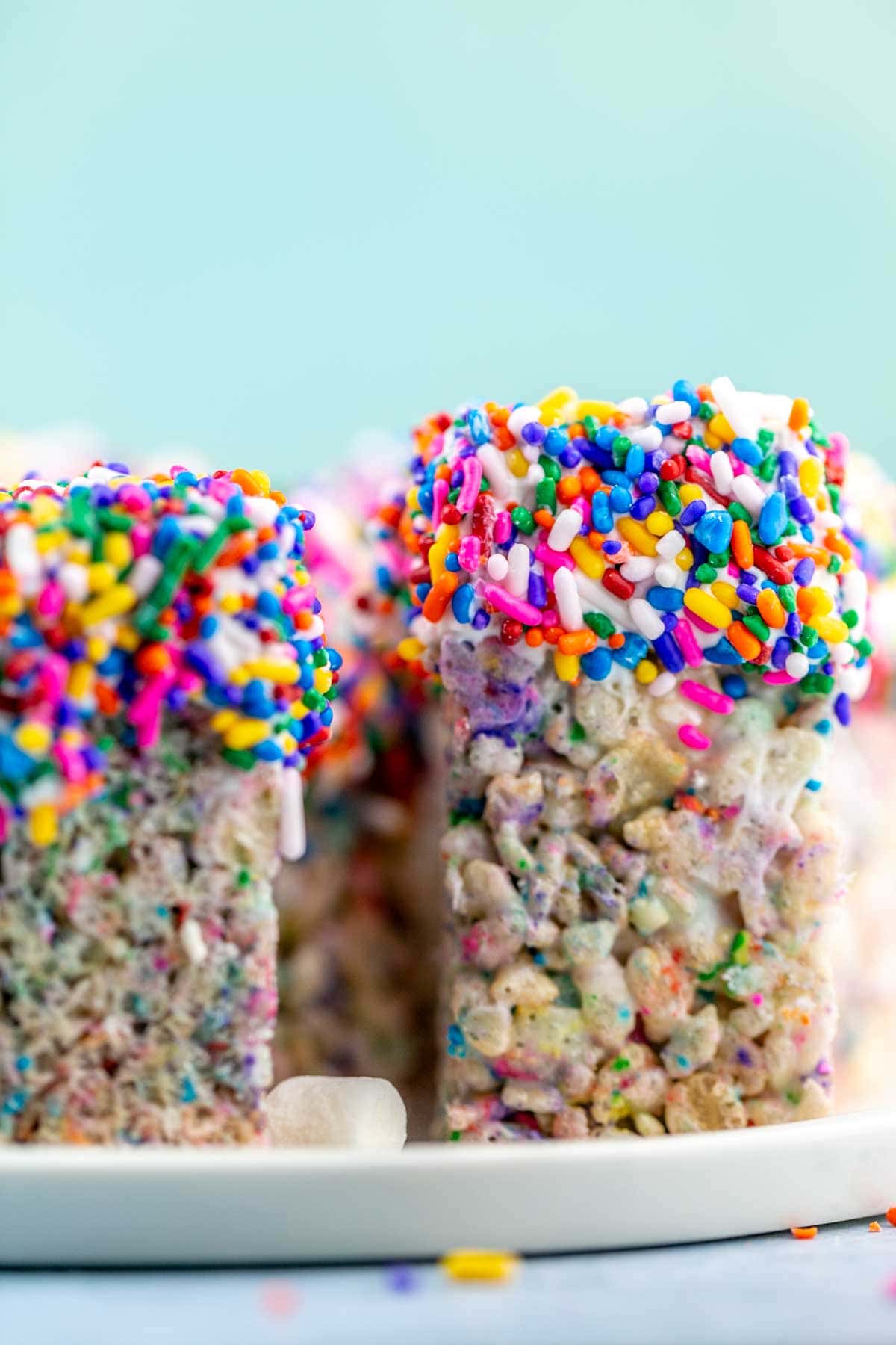 rice krispie treats standing upright with one end dipped in chocolate and covered in sprinkles.