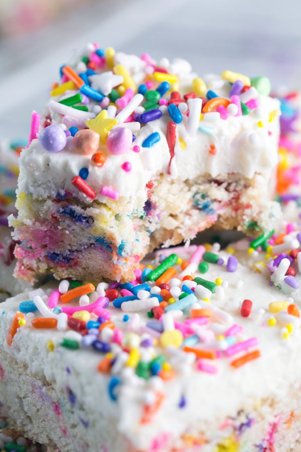 thick sugar cookie bar covered with frosting and sprinkles with one bite taken out of the cookie bar.