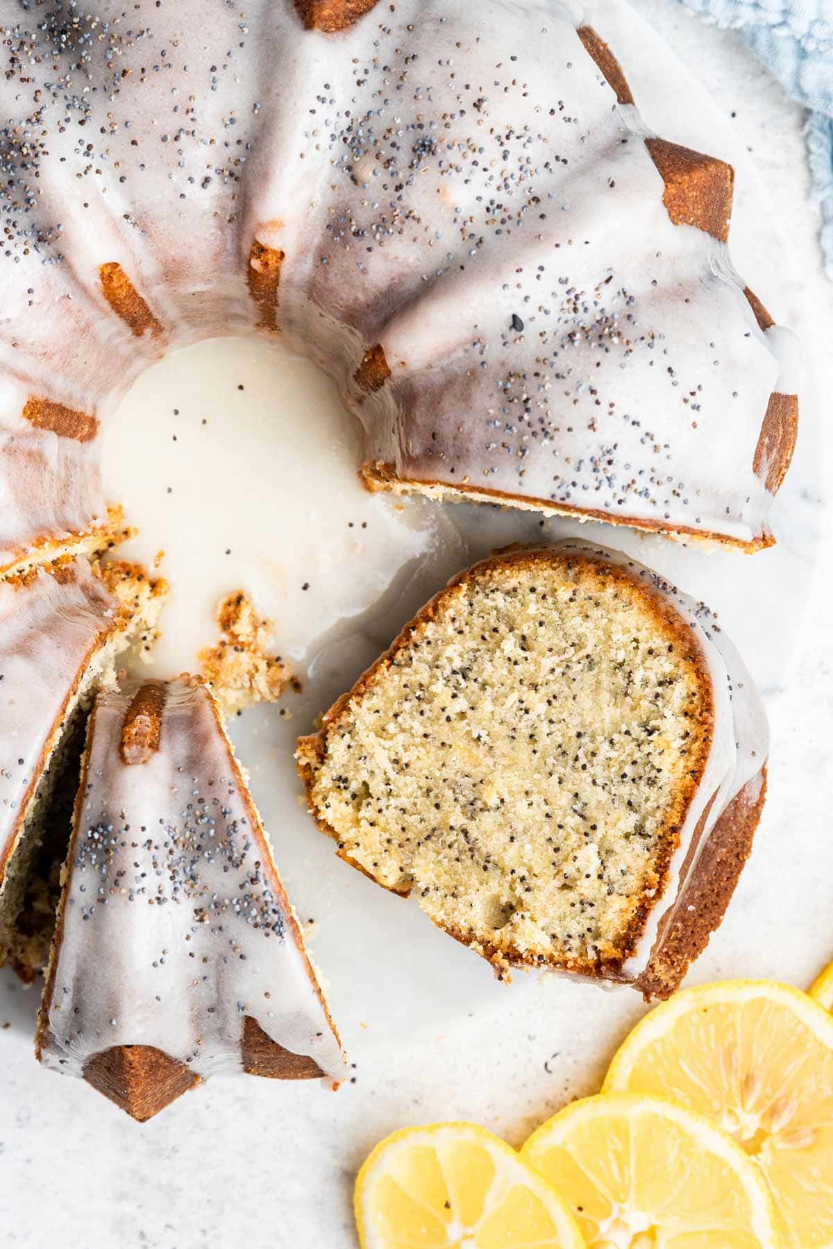 overhead view of a lemon poppy bundt cake next to slices of lemon.