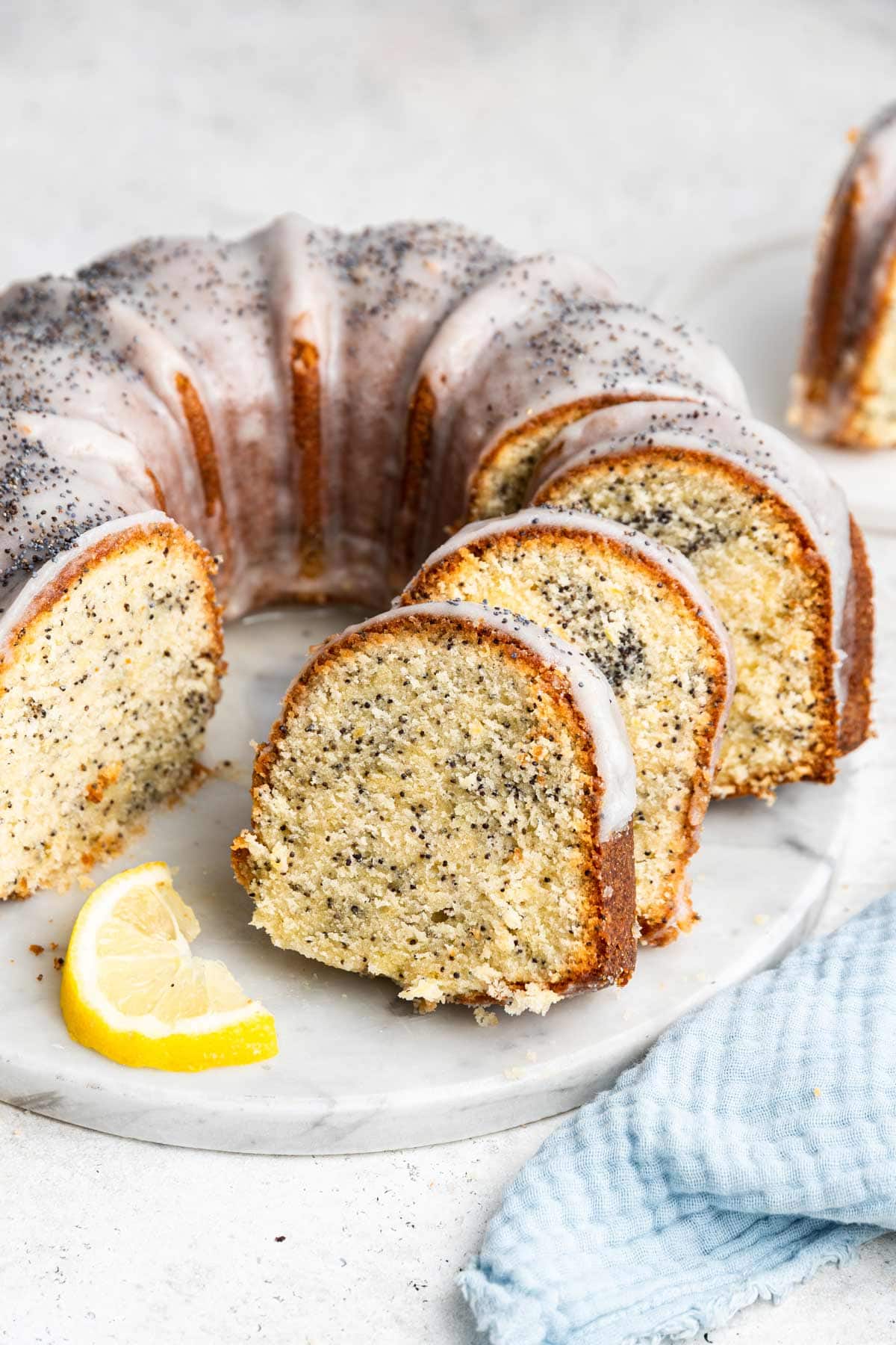 lemon poppy pound cake baked in a bundt pan with slices cut and stacked leaning against each other.