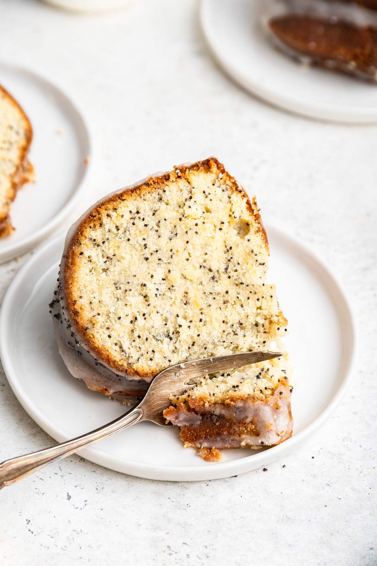 slice of lemon poppy pound cake on a plate with a fork.