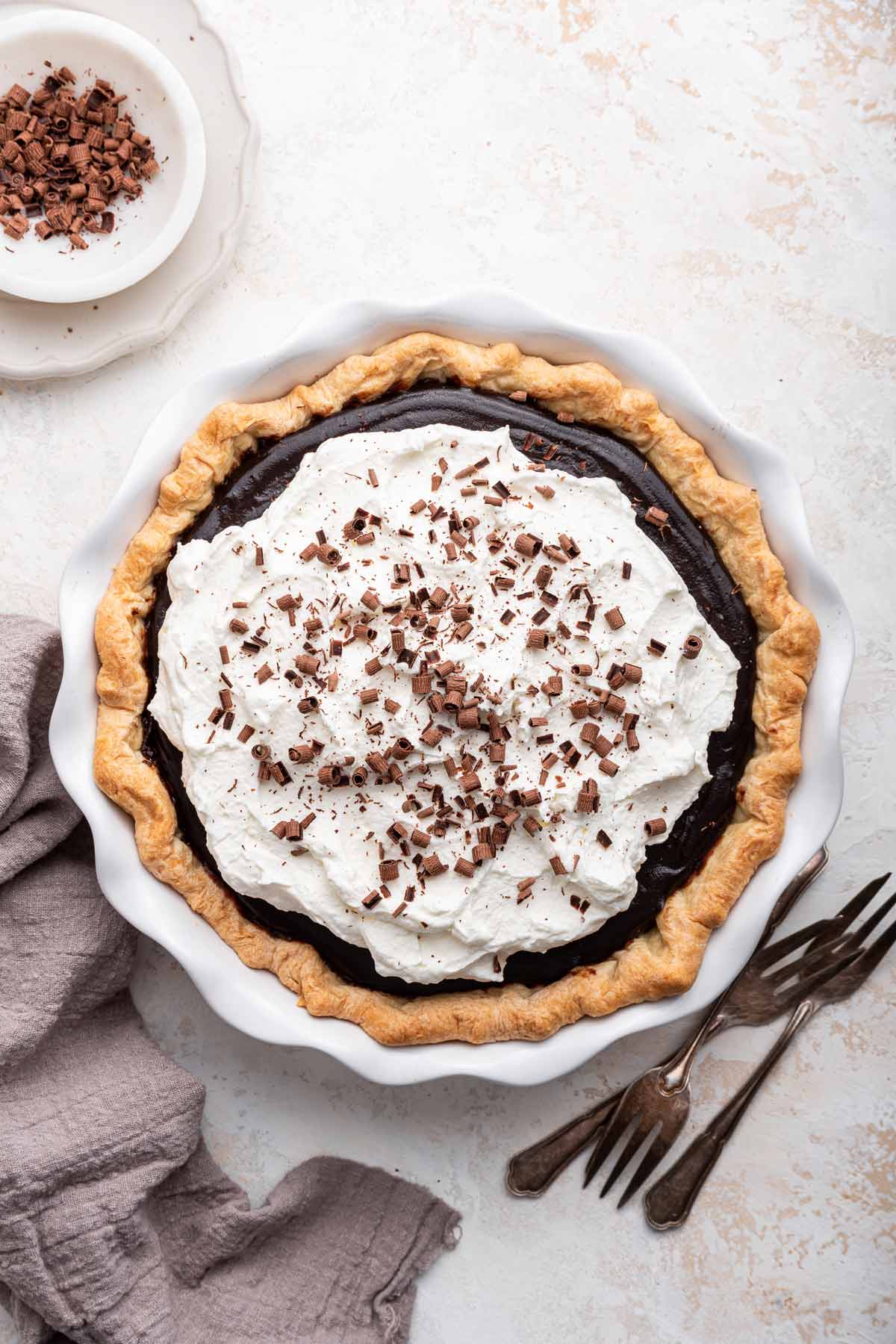 overhead view of a chocolate cream pie covered with whipped cream and chocolate shavings.