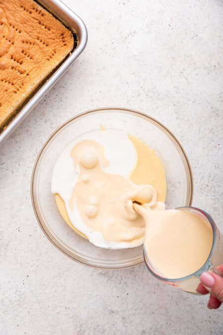 mixing together three kinds of milk in a glass mixing bowl.