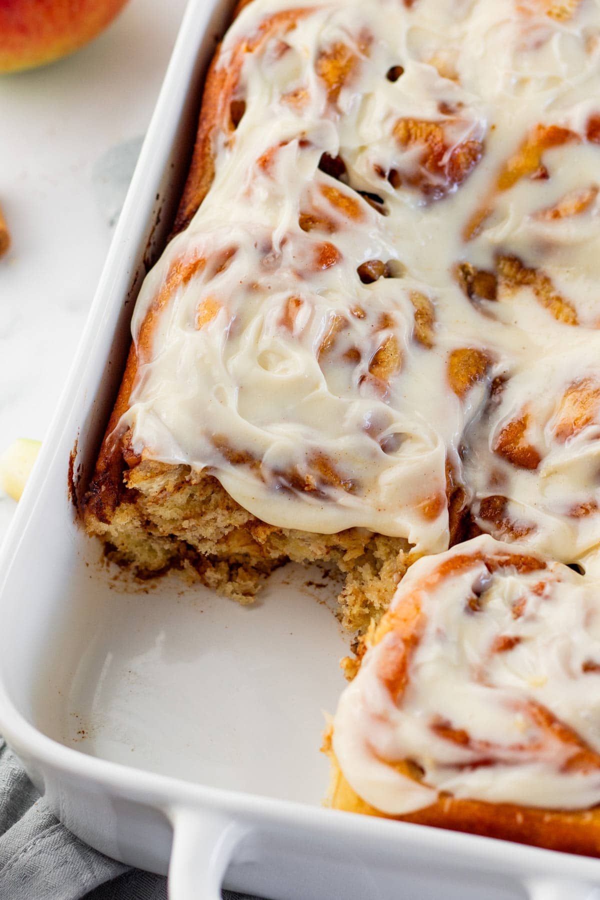 close up view of freshly baked apple pie cinnamon rolls nestled together in a pan.