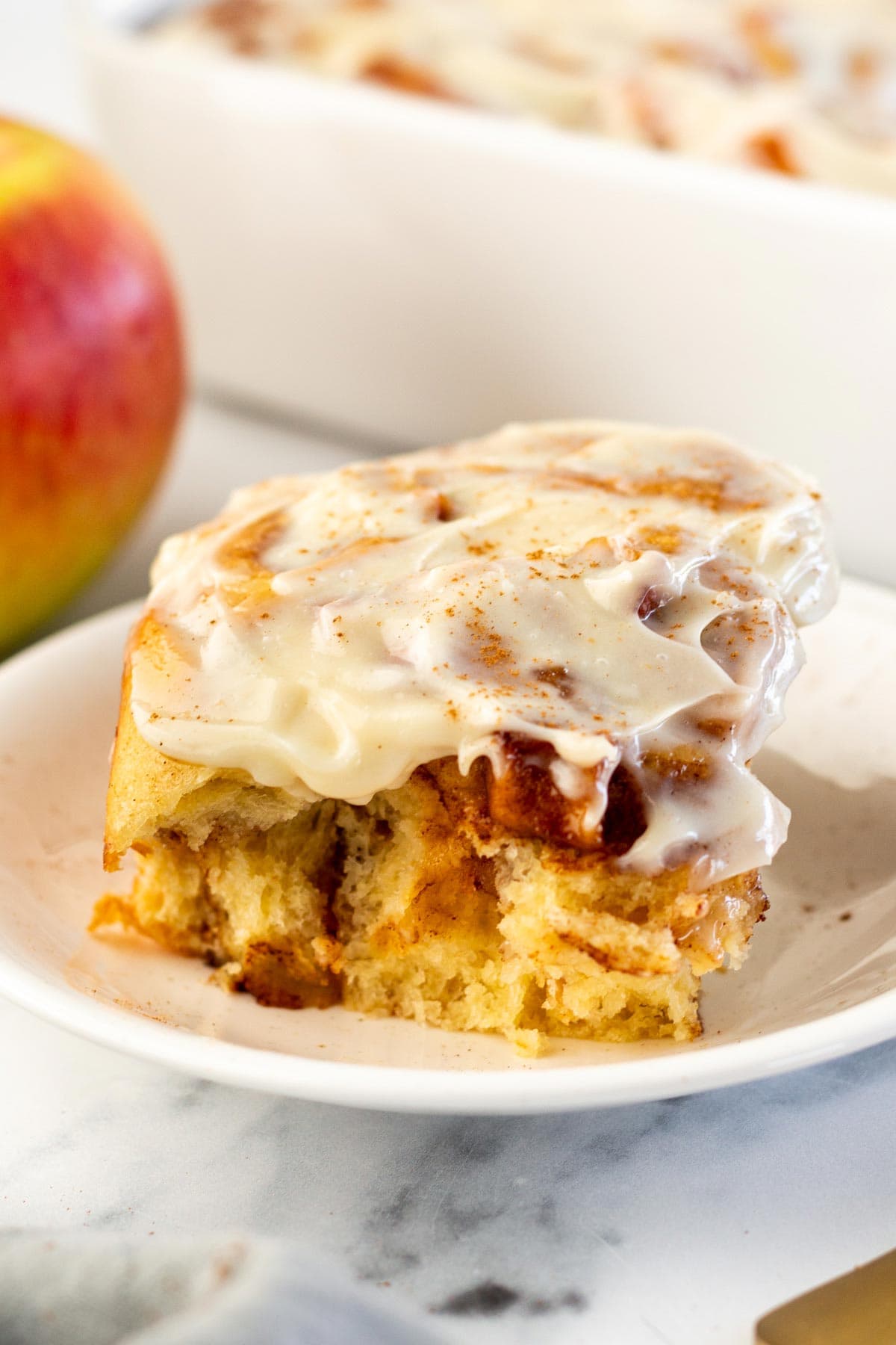tall fluffy cinnamon roll coverd with cream cheese frosting.