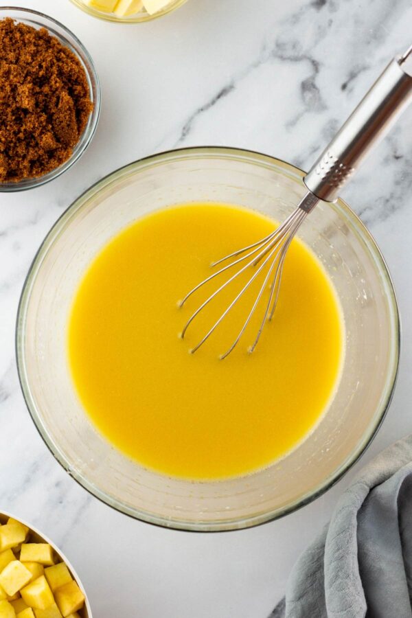 glass mixing bowl with eggs whisked into milk.