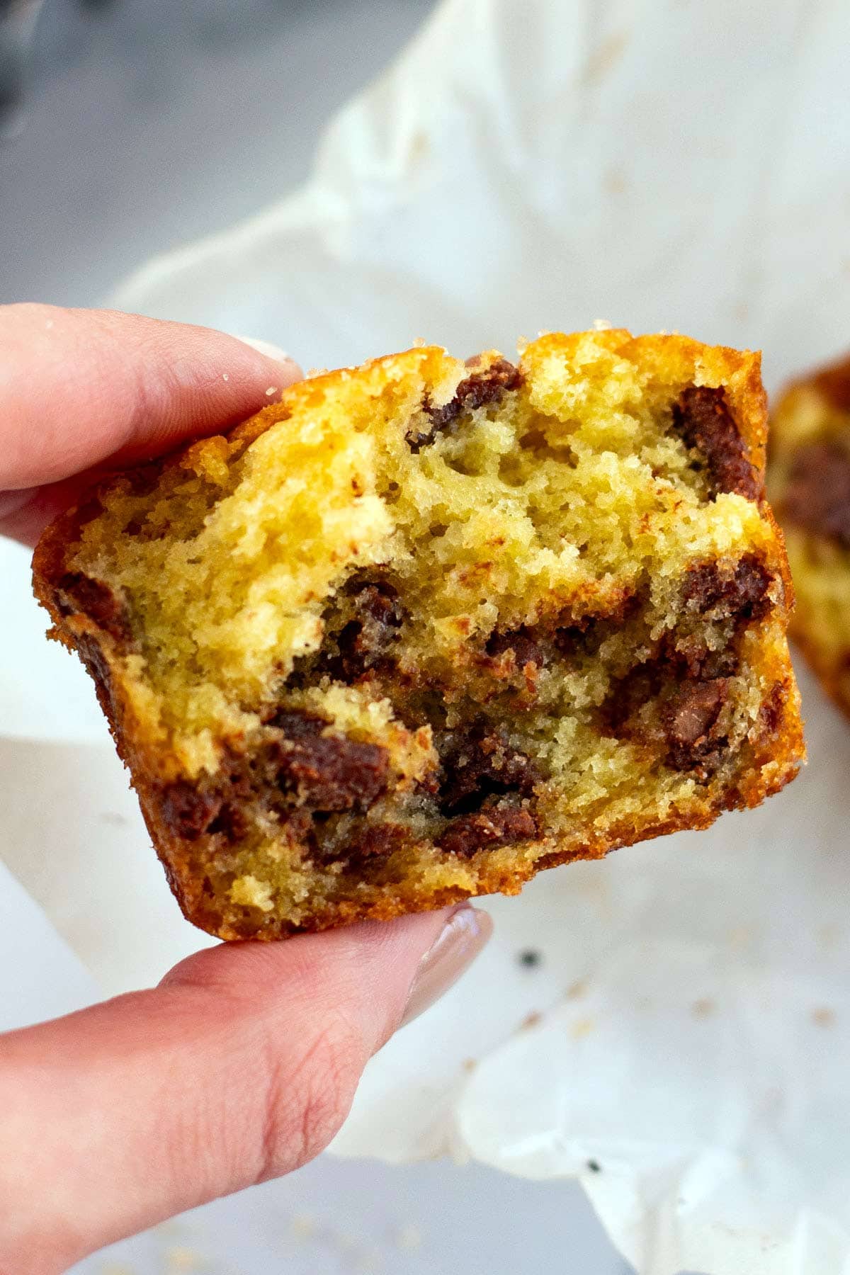 hand holding half of a chocolate muffin showing the fluffy interior.