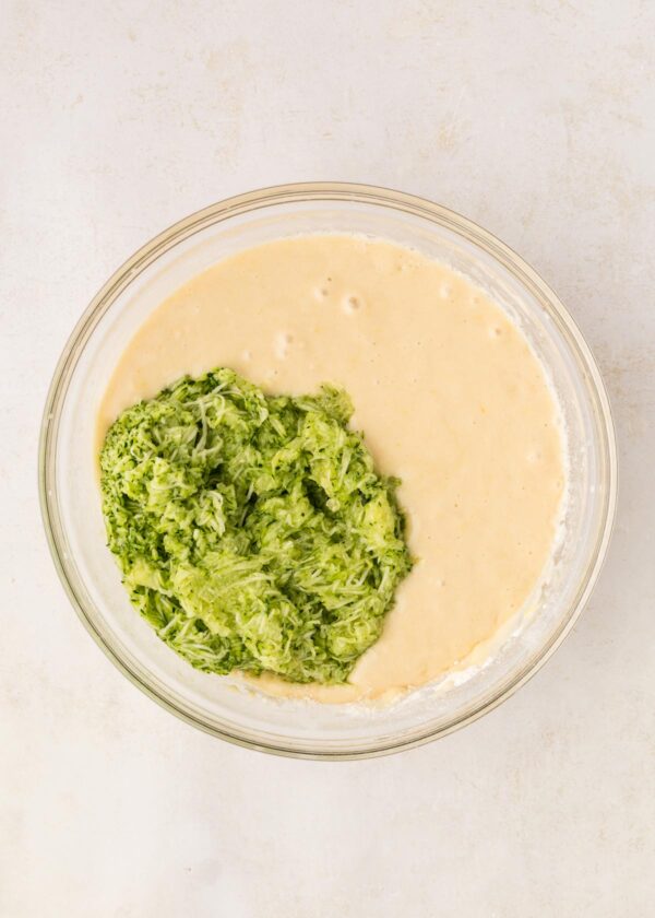 cupcake batter with a pile of shredded zucchini on top.