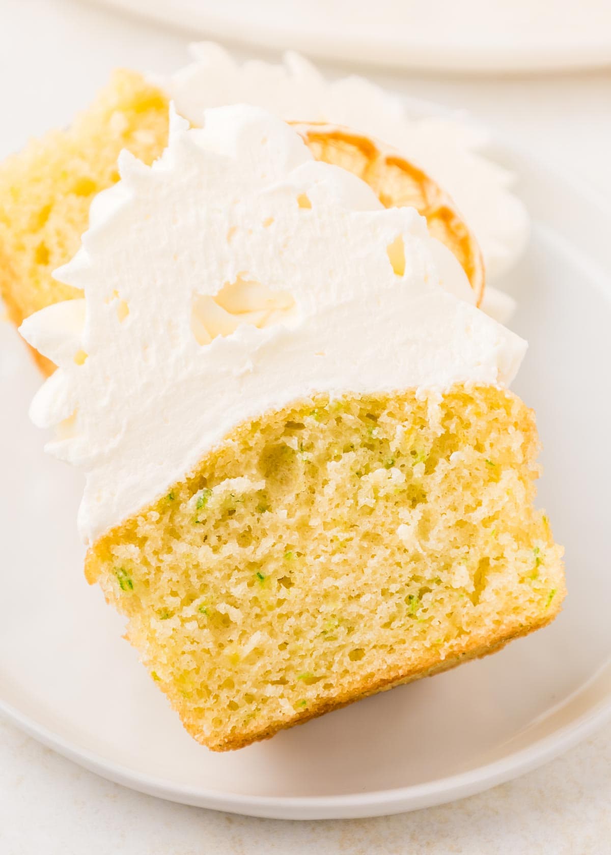 lemon cupcake cut in half showing the green flecks of zucchini inside.