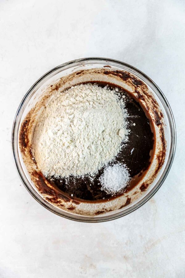 adding flour and salt to the wet ingredients for brownies.