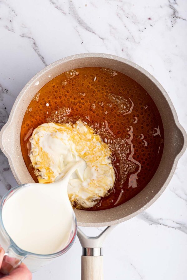 pouring heavy cream into a boiling sugar solution.
