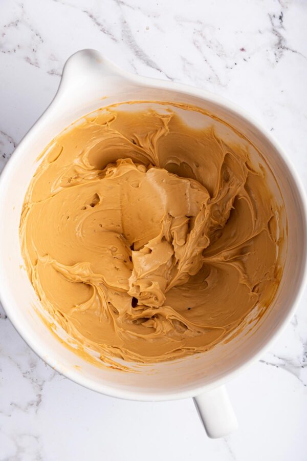 creaming together butter and caramel sauce to make caramel buttercream.