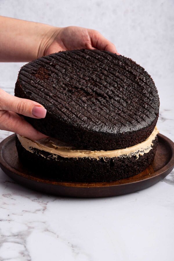 stacking a three layer chocolate cake.