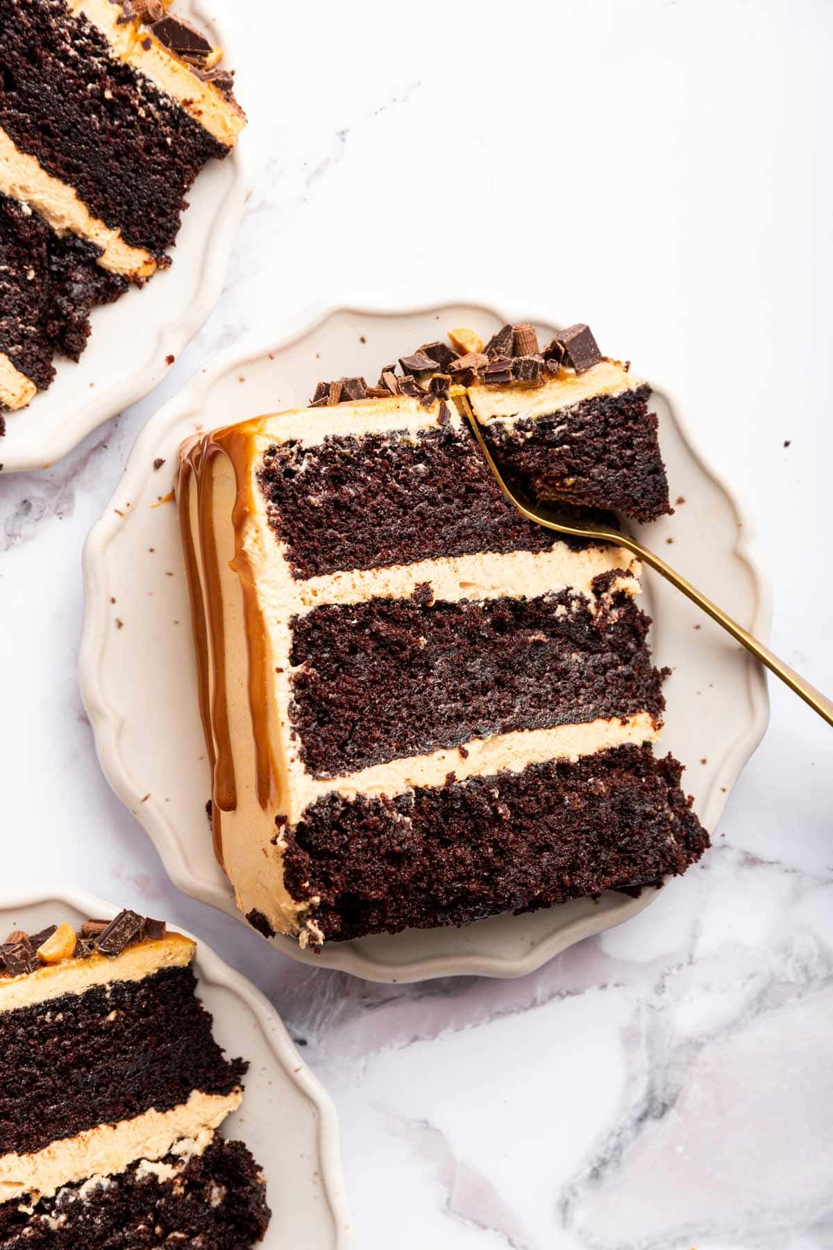 three slices of chocolate caramel cake on scalloped dessert plates.