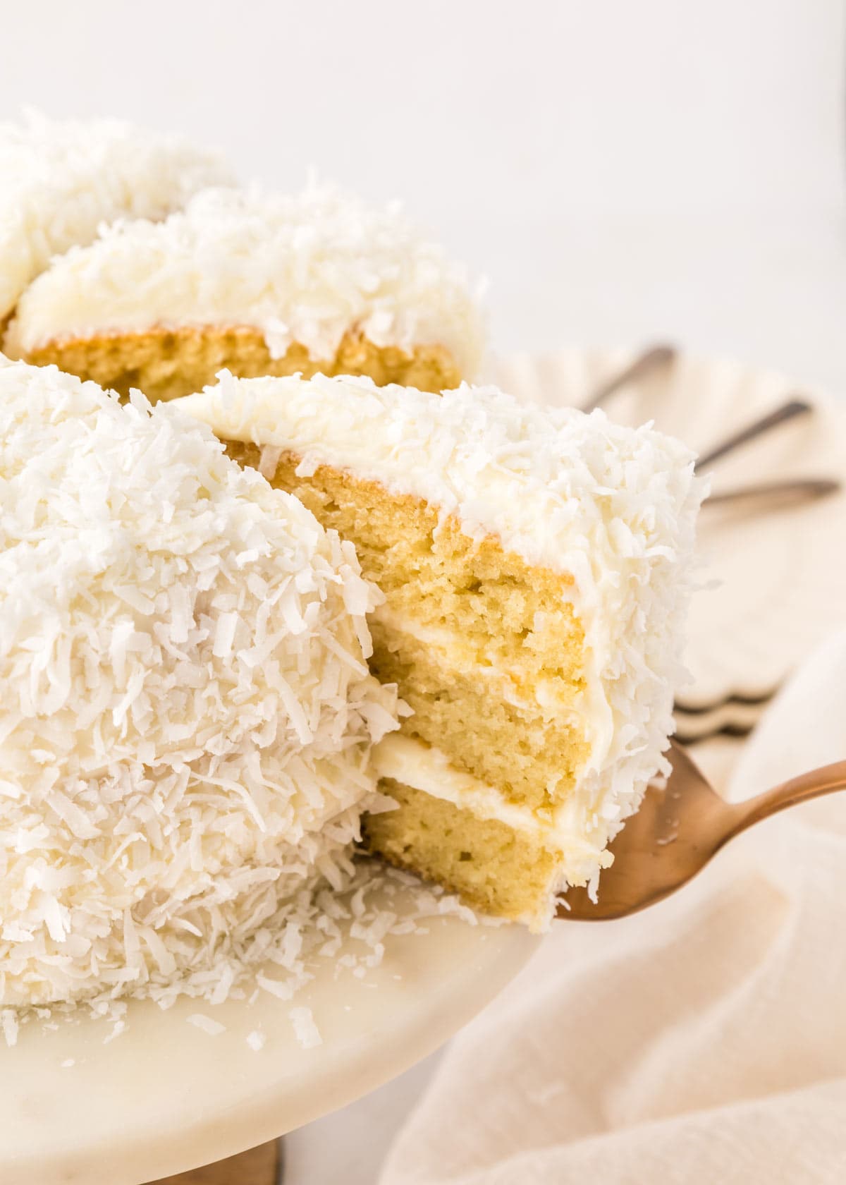 spatula lifting a slice of coconut cake from the rest of the cake.