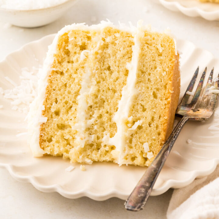slice of coconut cake on a scalloped dessert plate.