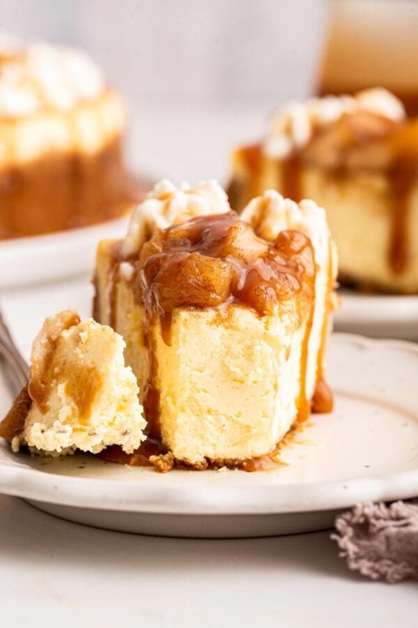 front view of a slice of caramel apple cheesecake with one forkful removed.