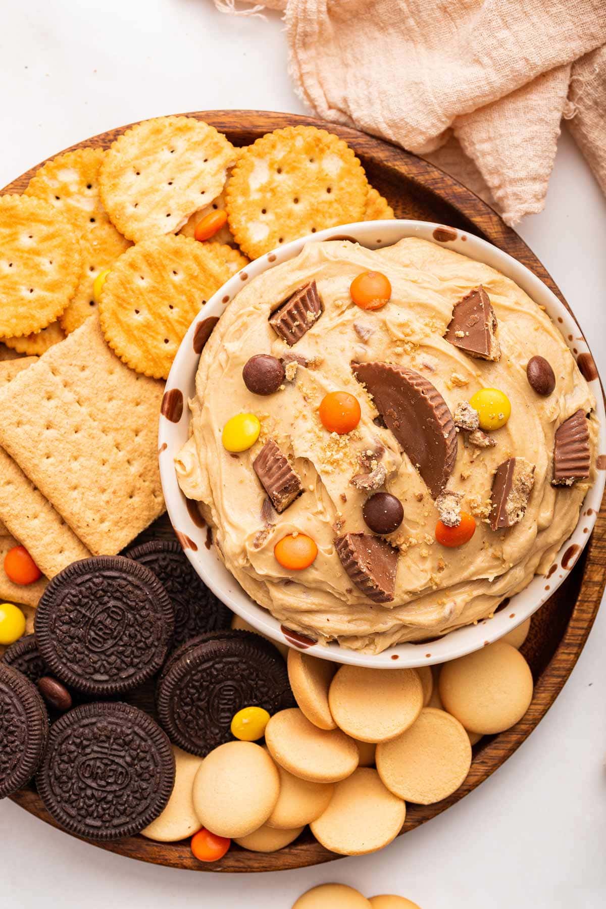 peanut butter dip surrounded by vanilla cookies, graham crackers, oreos, and ritz crackers.