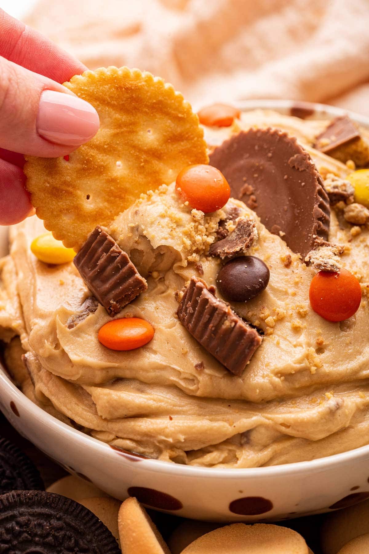 hand holding a Ritz cracker dipping it into peanut butter cup dip.