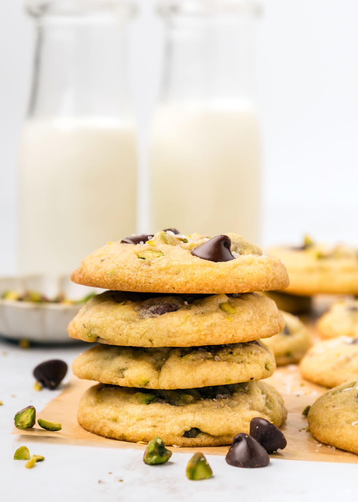 stack of chocolate pistachio cookies in front of two glasses of milk.
