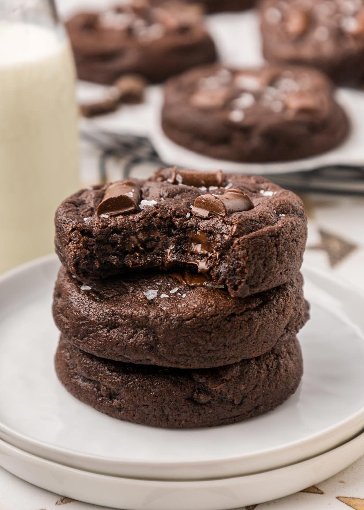 stack of cookies with a bite taken out of one showing the melty chocolate interior.