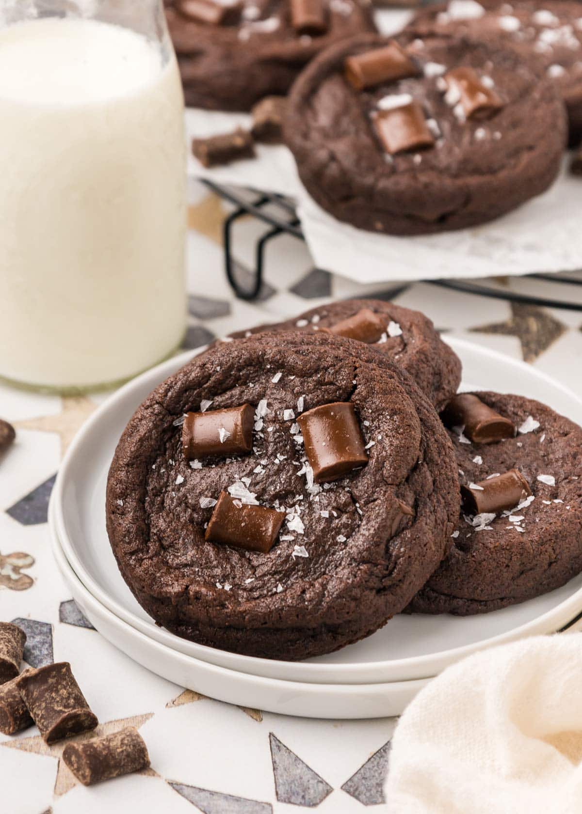 thick dark chocolate cookies sprinkled with sea salt on a white plate.