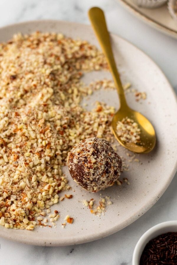 covering a bourbon ball with chopped nuts.