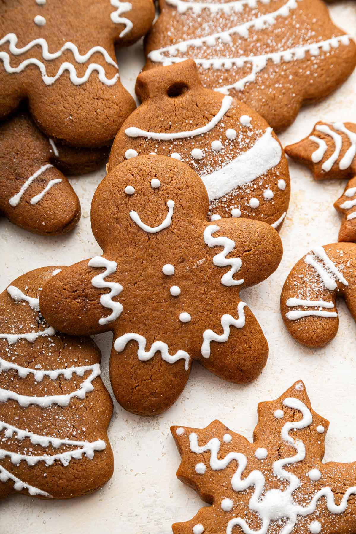 gingerbread man cookie next to christmas tree and snowflake cookies.