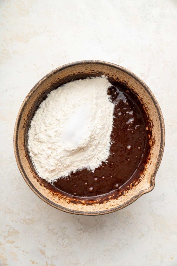 a pile of flour on top of a bowl of brownie batter.