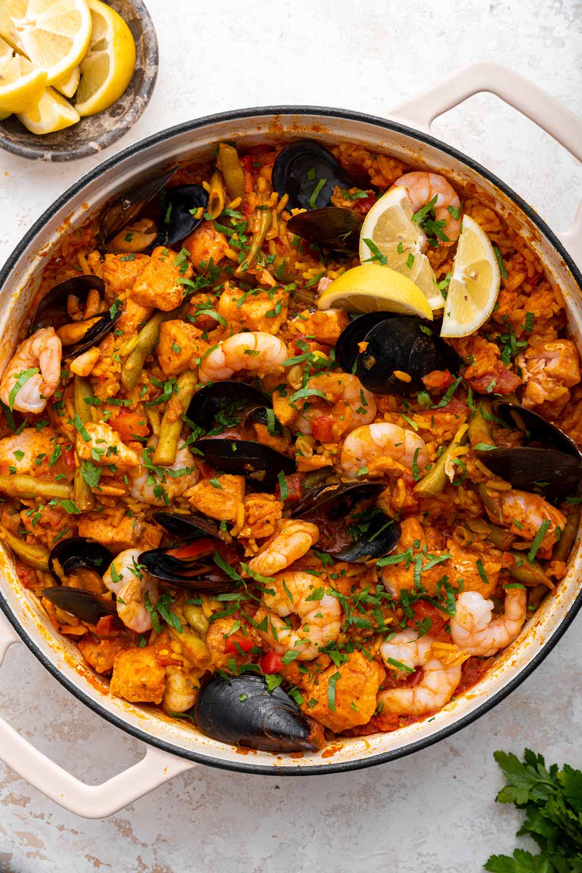 overhead view of a pan of salmon paella with vegetables and shellfish.