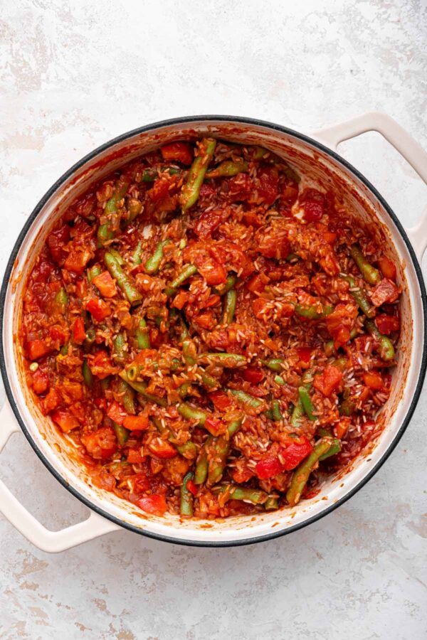 vegetables, crushed tomatoes, and rice mixed together in a pan.
