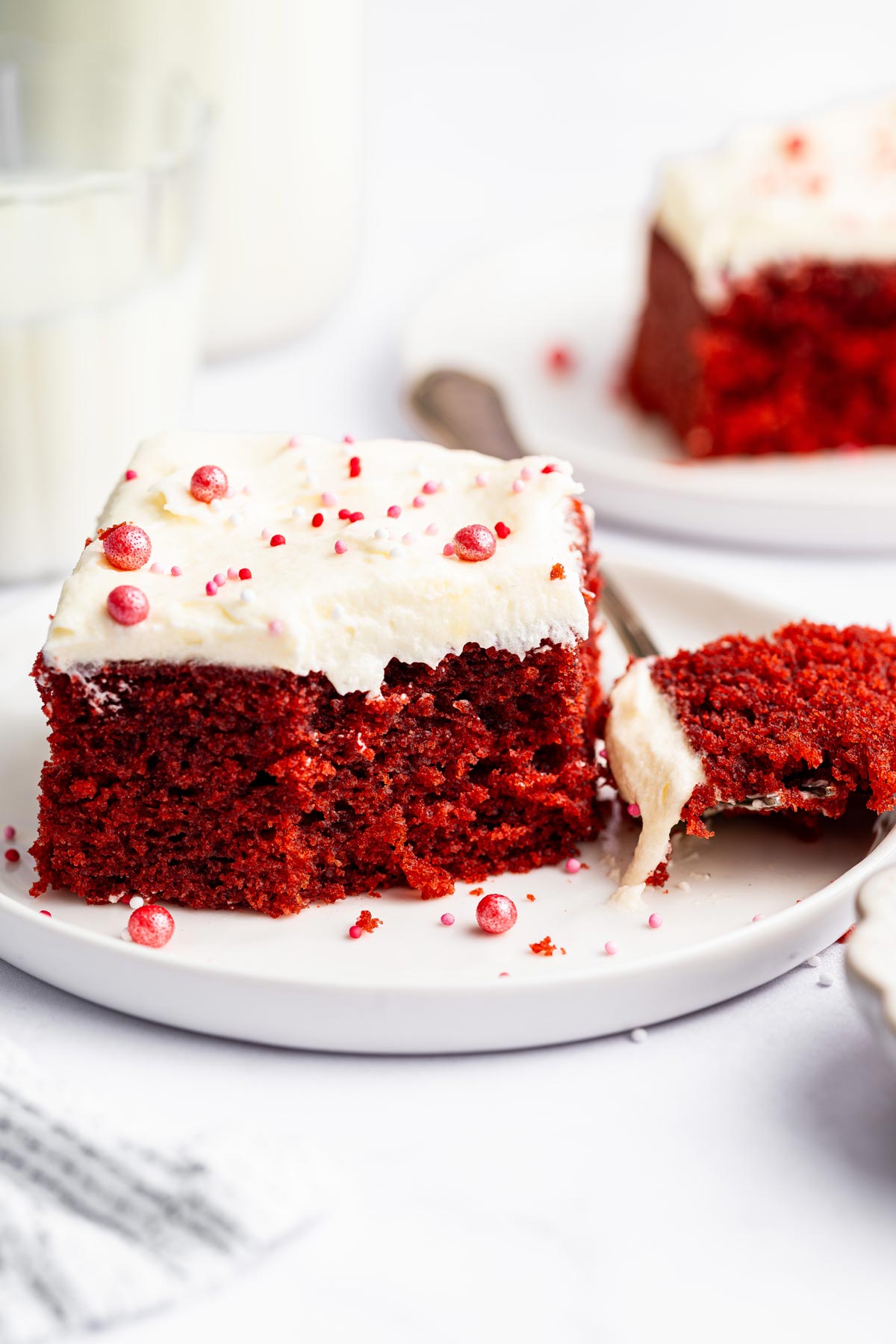 slice of red velvet sheet cake with one forkful removed and sitting on the plate.