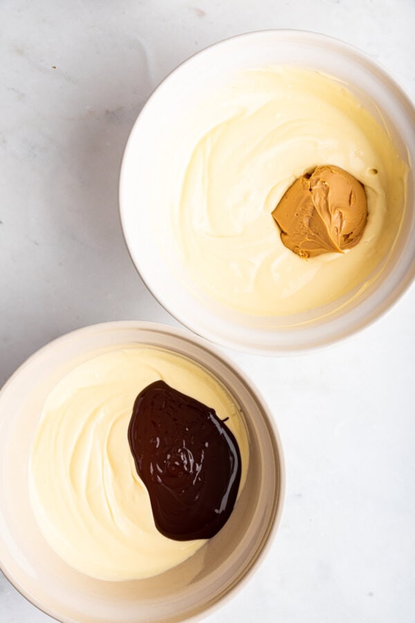 two bowls of cheesecake batter with melted chocolate and peanut butter.