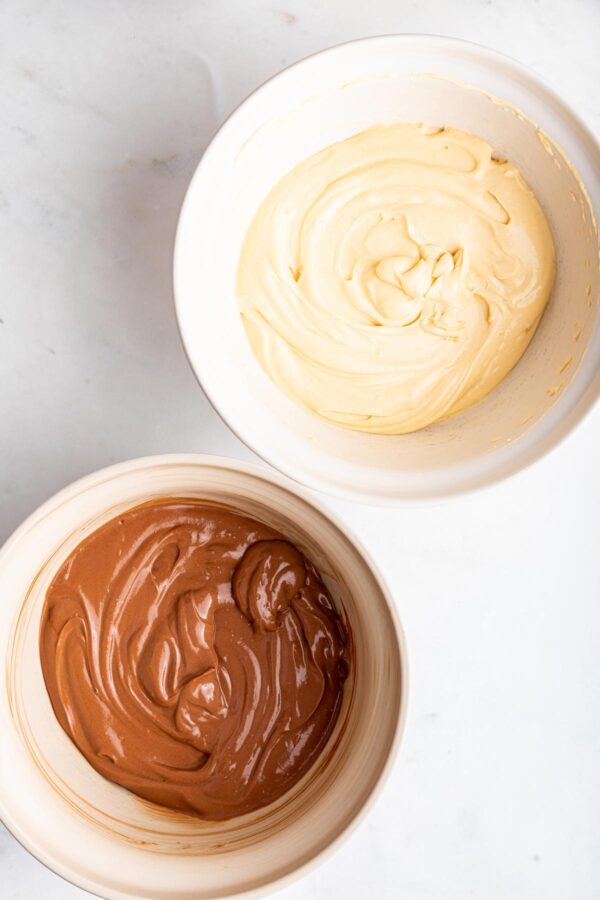 bowl of peanut butter cheesecake batter next to chocolate cheesecake batter.