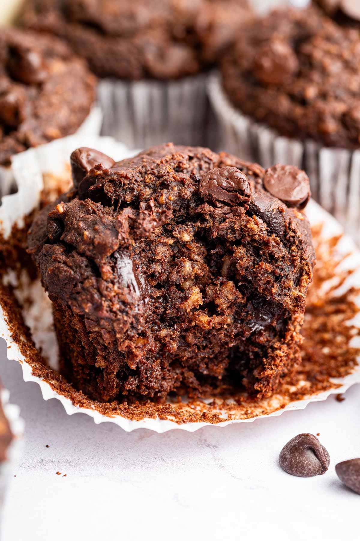 chocolate tahini muffins with a bite taken out showing the fudgy center.