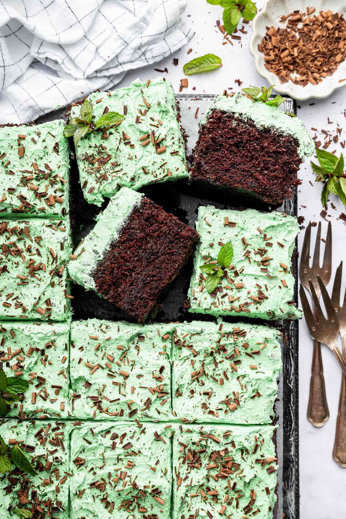 overhead view of a mint chocolate chip sheet cake with two slices turned on their sides.