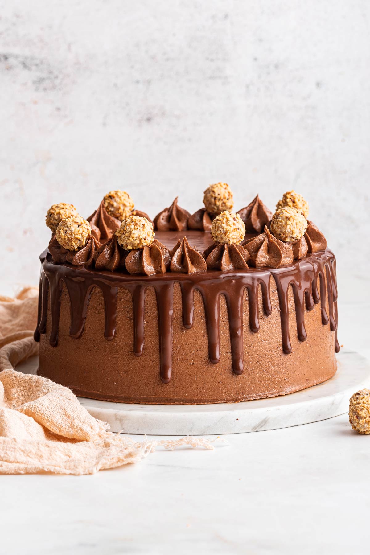 two layer chocolate hazelnut cake decorated with ganache and ferraro rocher.