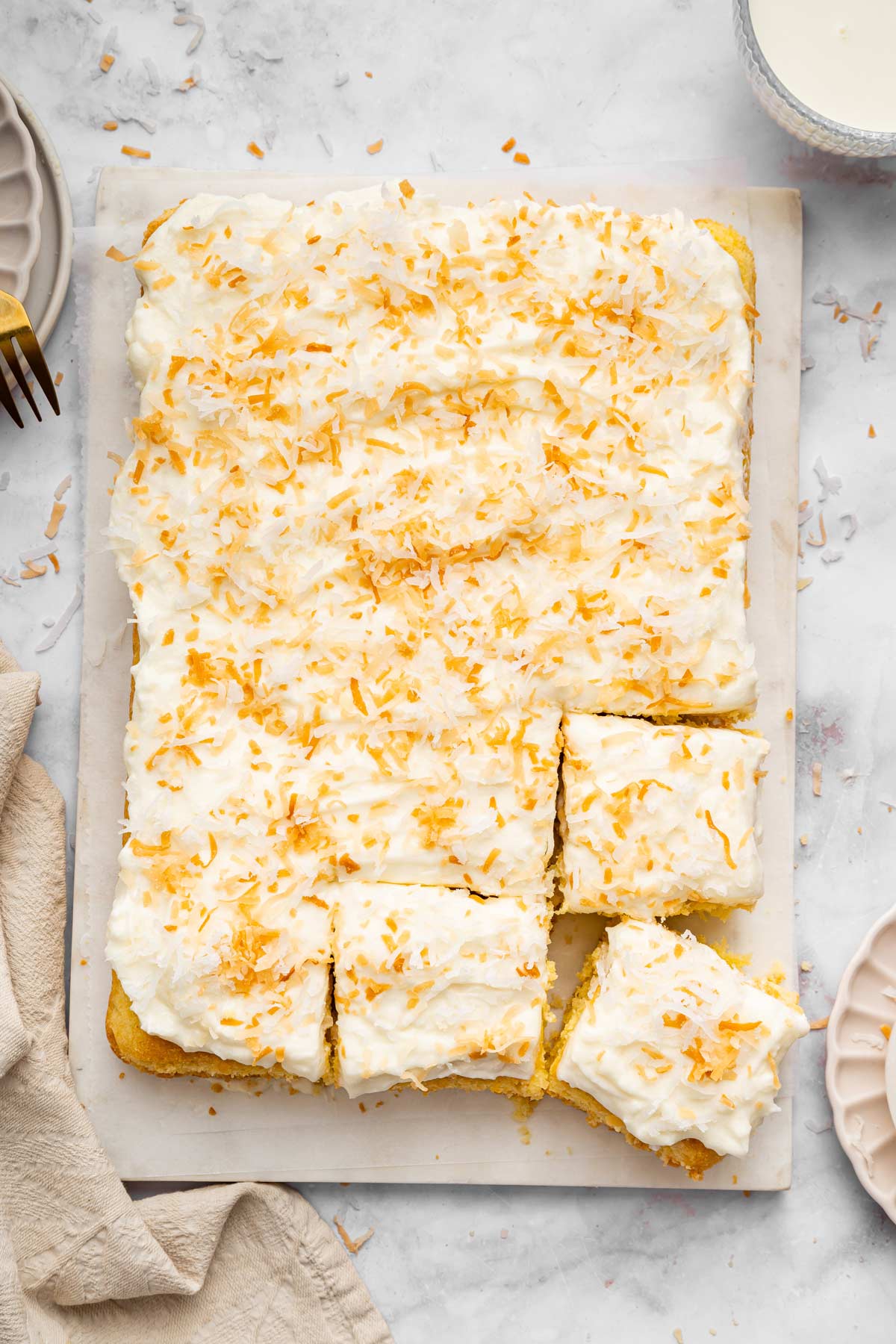 coconut sheet cake with cream cheese frosting on a serving board.