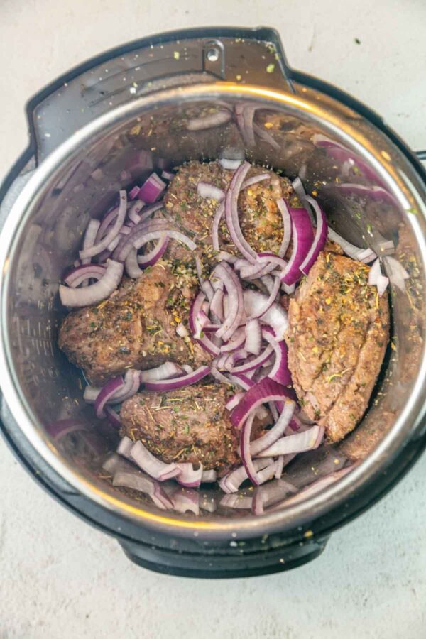 chuck roast and red onions in an instant pot before cooking.