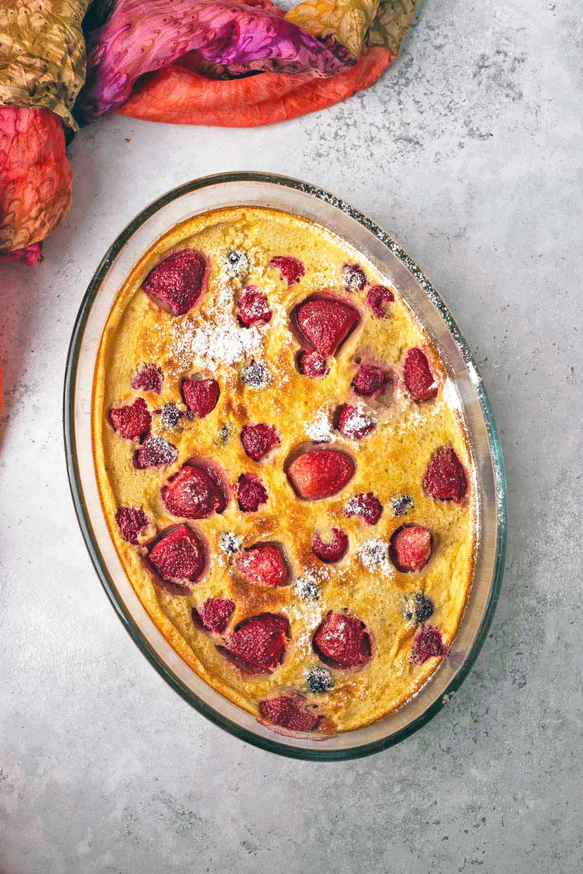 clafoutis baked with strawberries and blackberries in a glass serving dish.