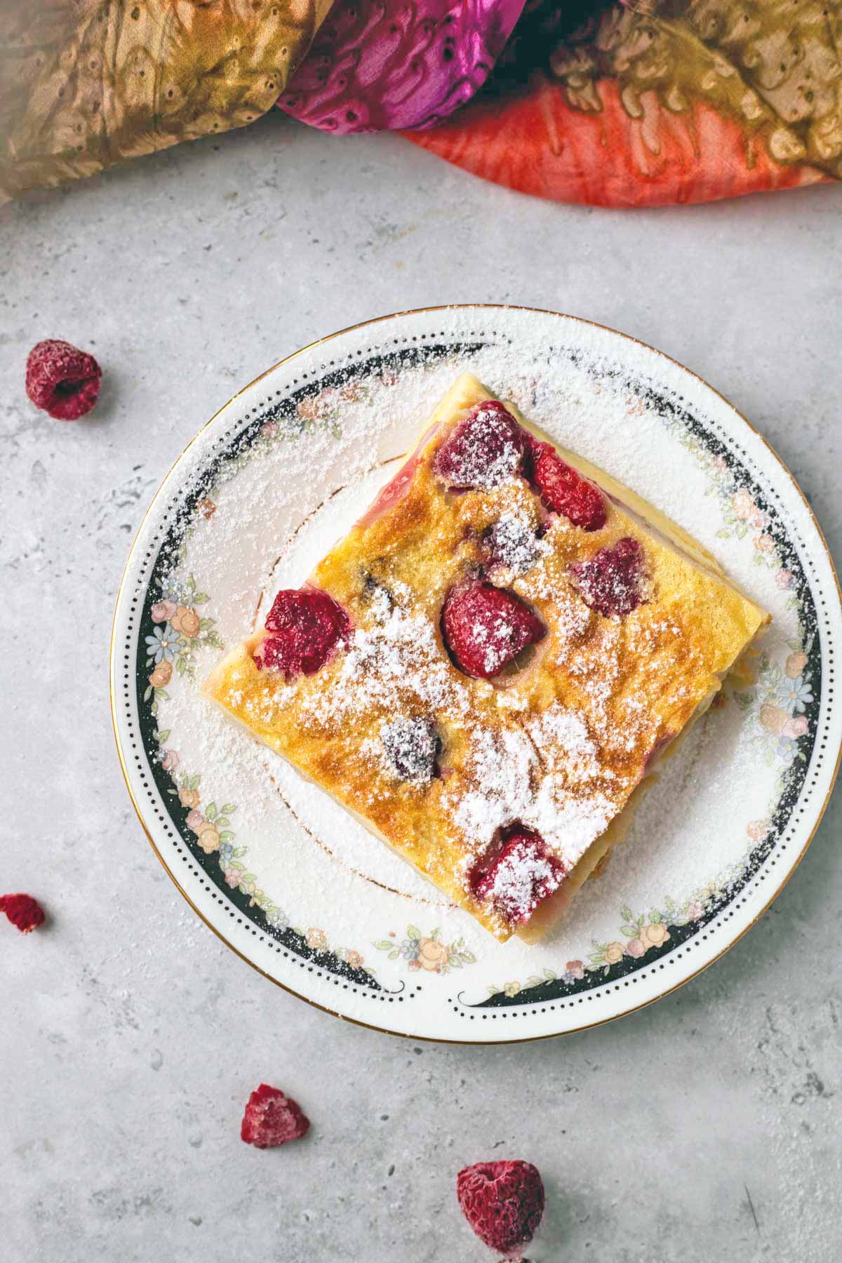 square of berry clafoutis dusted with powdered sugar.