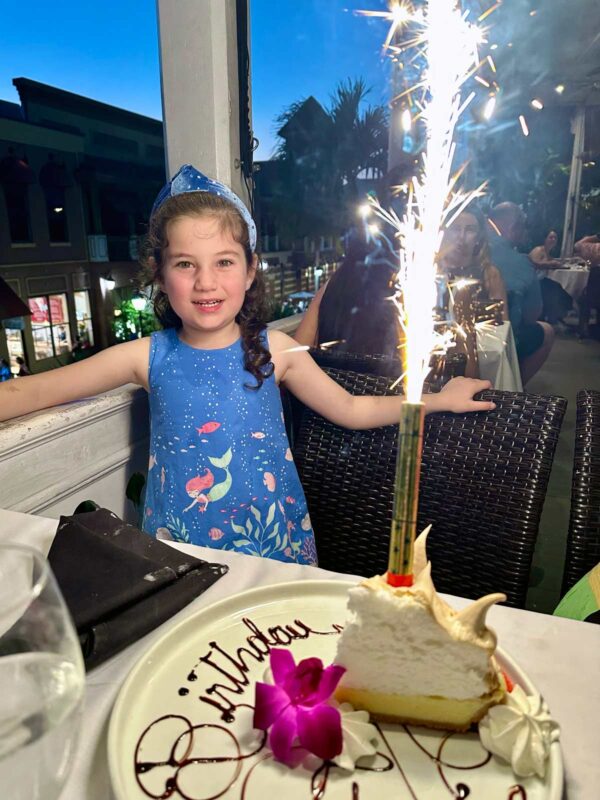 girl next to a slice of key lime pie with a huge pile of meringue topping.