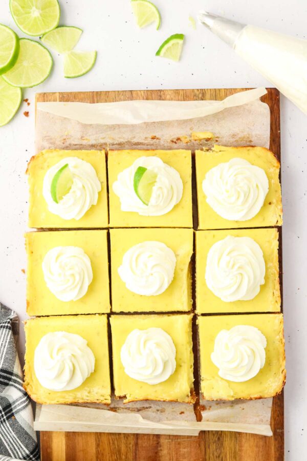 key lime pie bars with a swirl of whipped cream and slice of lime on top of each.