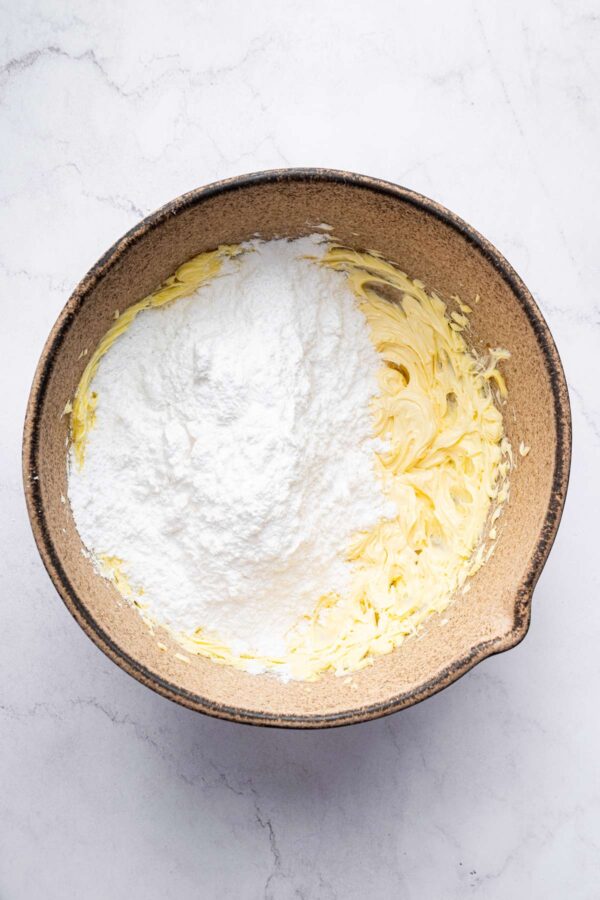 adding powdered sugar to whipped butter to make frosting.