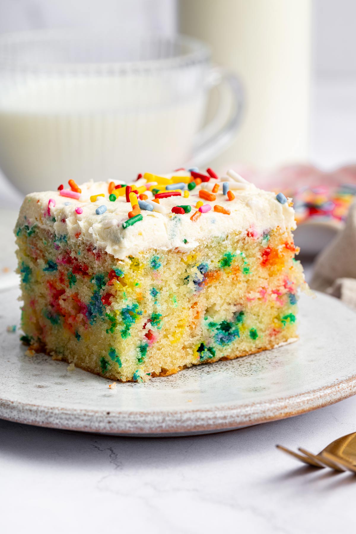 slice of funfetti sheet cake showing the fine crumb and all the sprinkles inside.