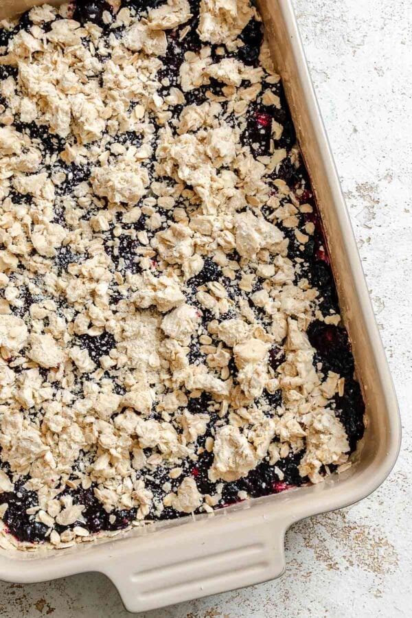 crumble topping spread over berry crumb bars.