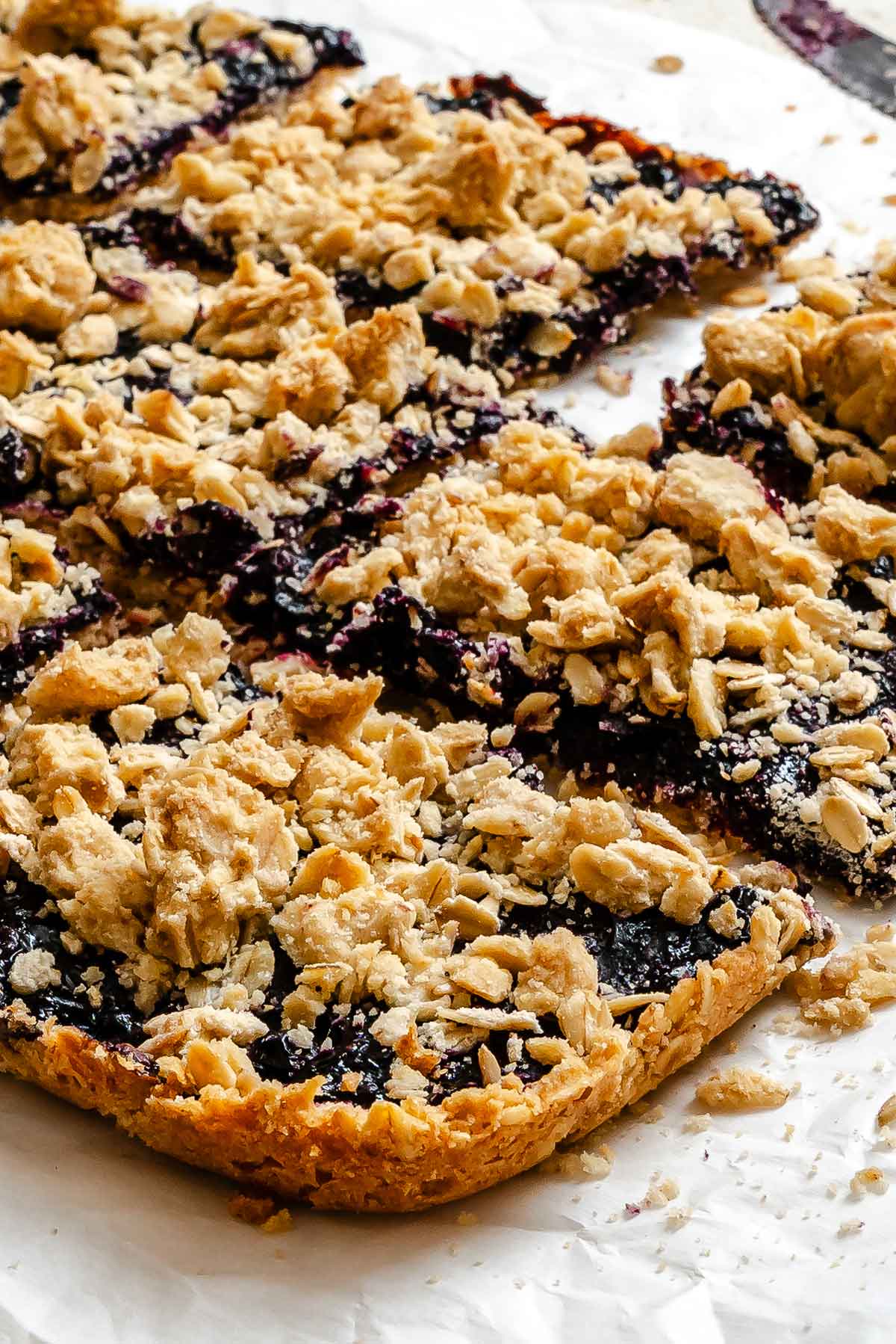 side view of berry crumble bars showing the golden brown crunchy oatmeal shortbread crust.